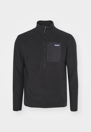 Black fleece pullover with a high collar, zip closure, and textured pattern. Features a chest pocket in a contrasting fabric.