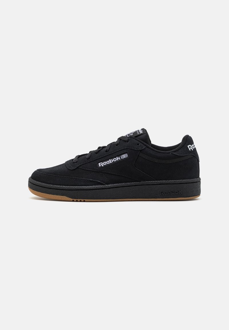 Basket basse noire Reebok avec semelle en gomme, lacets à l'avant et logo blanc Reebok sur le côté, la languette et le talon.