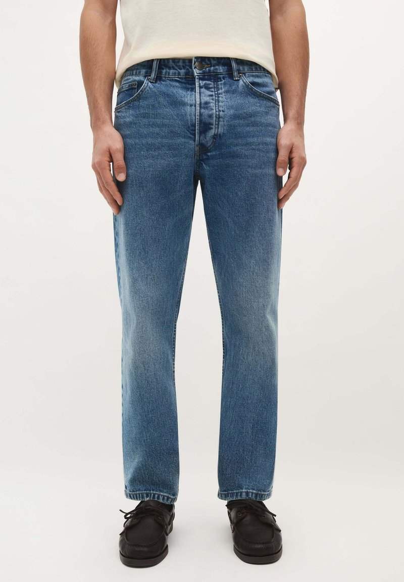 Jeans de denim azul con un diseño de pierna recta, que presentan una cintura de altura media y un estilo clásico de cinco bolsillos. La tela tiene un acabado texturizado sutil.