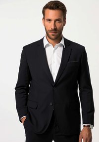 Marineblauwe pakjack gemaakt van gladde stof, met twee knopen, zijzakken en een subtiele detail van een pochet. Witte dress shirt eronder.