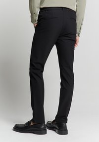Zwarte op maat gemaakte broek met een gladde textuur, slim fit, elastische tailleband en achterzakken. Gekocht met zwarte loafers.