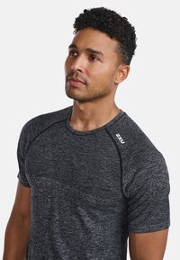 Kortärmad träningsskjorta i mörkgrått tyg med ett strukturerat mönster. Har rund halsringning och kontrasterande svart sömnad. Logotyp på axeln.