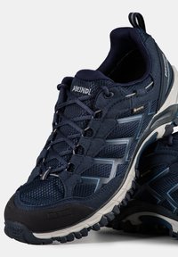 Męskie buty trekkingowe w ciemnym granacie i szarości, z siateczkową cholewką, bezszwowymi nakładkami oraz wytrzymałą gumową podeszwą z teksturowanym bieżnikiem.