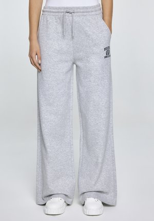 Lichtgrijze, wijde sweatpants gemaakt van zacht materiaal. Heeft een verstelbare tailleband en zijzakken. Bevat een klein bedrukt logo op het bovenbeen.