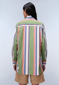 Camicia a maniche lunghe con righe verticali in verde, bianco, rosa e blu. Realizzata in cotone, presenta un dettaglio con bottone sulla manica.