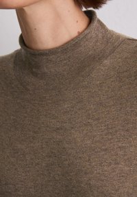 Brązowy sweter w serek o miękkiej fakturze, z wysokim kołnierzem i dopasowanym krojem. Tkanina ma subtelny wzór splotu.
