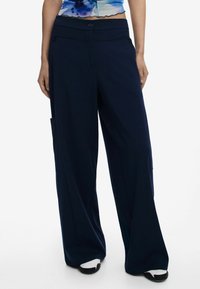 Pantaloni a gamba larga color navy realizzati in tessuto liscio, dotati di una vita alta, chiusura con bottone e tasche laterali per una maggiore praticità.