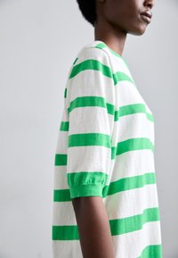 Maglione lavorato a maglia con strisce orizzontali verdi e bianche, maniche a palloncino corte e collo rotondo. Texture morbida con una vestibilità rilassata.