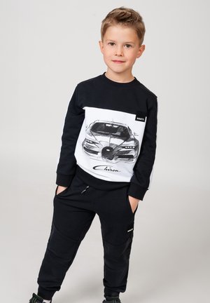 Black and white sweatshirt featuring a car illustration, paired with black pants. The outfit has a sporty design and comfortable fit.