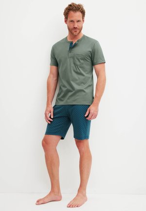 Men's short-sleeve, olive green modal T-shirt with a chest pocket, paired with teal shorts featuring a small white dot pattern.