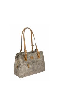 Sac fourre-tout en tissu tressé brun avec des accents en cuir tan, deux poignées pour l'épaule, une poche zippée à l'avant et un patch avec logo à l'avant.