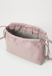 Borsa a sacchetto in ecopelle rosa con una morbida texture, forma rettangolare e interni rifiniti con cura. Presenta una tracolla intrecciata e cuciture sottili.