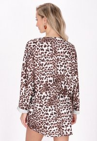 Halenka s leopardím potiskem v hnědých a krémových barvách, s dlouhými rukávy a uvolněným střihem. Má bílý límec a je vyrobena z měkké látky.