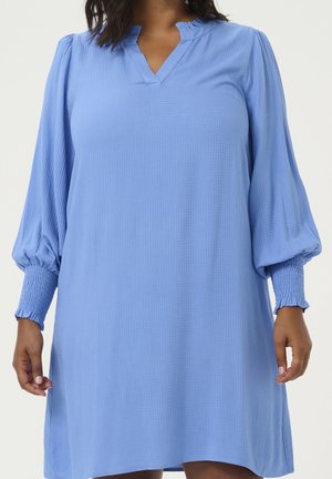 Luźna niebieska sukienka z teksturowanej tkaniny, z marszczonymi bufkami i ściągaczami na mankietach, noszona przez osobę o średnio-ciemnym odcieniu skóry.