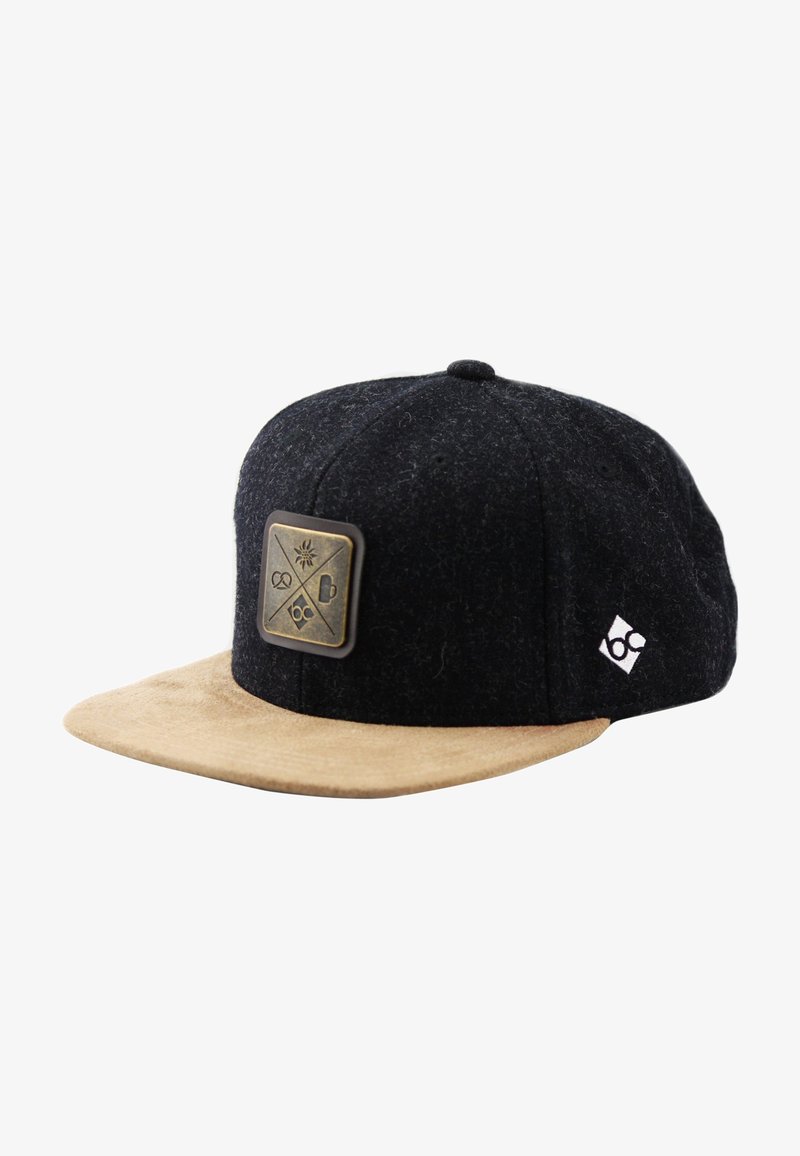 Casquette snapback noire et fauve avec une visière en daim beige, une plaque métallique à l'avant ornée de quatre icônes, et un petit logo blanc sur le côté.
