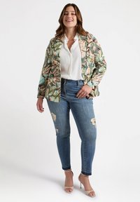 Floral-patterned fabric blazer in green, pink, and beige, paired with light-wash ripped skinny jeans and nude high-heeled sandals.