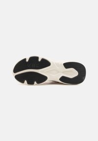 Semelle de sneaker présentant une surface en caoutchouc noir texturé, une semelle intermédiaire crème, avec des motifs de bande de roulement complexes et un logo de marque visible.