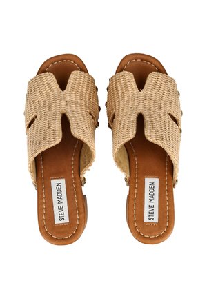 Par af slip-on sandaler med lysebrun lædersål og vævet beige stofoverdel med "Steve Madden" label indeni hver fodseng.