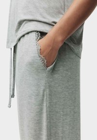 Lys grå loungedragt sæt med en løs top med en blød tekstureret finish og bukser med blondebesatte lommer, der fremviser afslappet komfort.