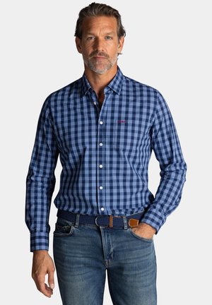 Blauwe gestructureerde blouse met lange mouwen, met verschillende tinten blauw en wit, gecombineerd met een bruine en blauwe gevlochten riem.