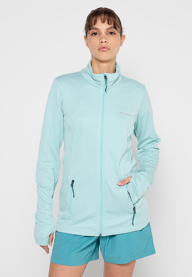 Hellblaues Fleece-Jacke mit Stehkragen, zwei Reißverschlusstaschen und langen Ärmeln, die eine strukturierte Oberfläche und dezente Markenkennzeichnung aufweist.