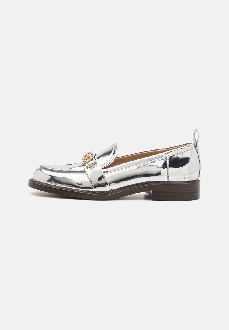 Metallic silver loafer made from shiny, smooth material. Features a small heel, round toe, and decorative gold buckle on the strap.
