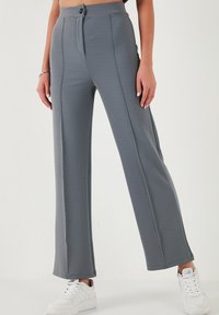 Gray wide-leg pants made from textured fabric, featuring a front button closure, vertical seams, and paired with white sneakers.