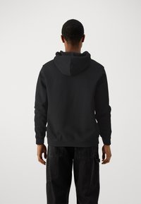 Sweatshirt à capuche noir en tissu doux. Il présente une poche kangourou, des poignets côtelés et une coupe décontractée. Design minimaliste sans motifs.