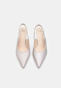 Para srebrnych skórzanych butów typu slingback z wąskim noskiem i niskim obcasem, markowych "Bata," pokazanych z góry na białym tle.