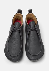 Scarpe in pelle nera con una superficie liscia, dotate di allacciatura e interno morbido, presentate da una vista dall'alto.