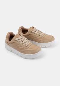 Beige sportcipők sima és suede textúrák keverékével, vastag fehér talppal, kerek fűzőkkel és diszkrét oldali varrási részletekkel.