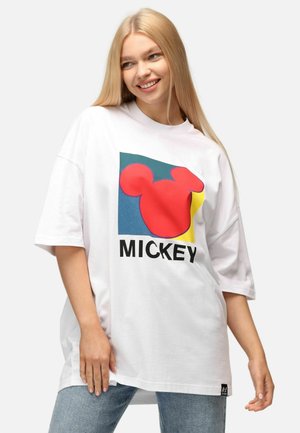 Camiseta blanca de gran tamaño con un gráfico colorido de la cabeza roja de Mickey Mouse y la palabra "MICKEY," con cuello redondo y mangas cortas.