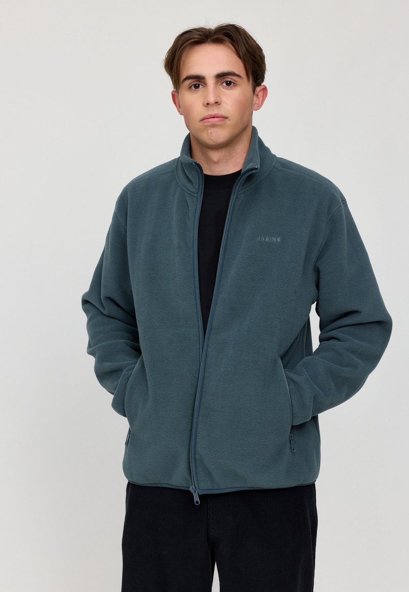 Fleecejacke in Dunkeltürkis mit vollem Reißverschluss, hohem Kragen und Seitentaschen. Weicher Stoff und minimale Markenkennzeichnung auf der Brust.