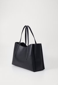 Sac tote en cuir noir avec deux longues poignées, forme structurée, texture lisse et design ouvert. Marque minimaliste dans un emplacement discret.