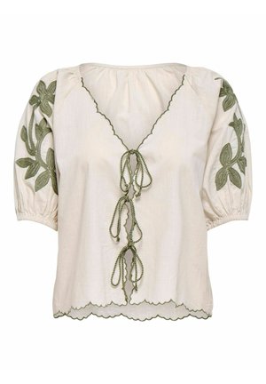 Blouse crème avec des accents floraux verts brodés, manches bouffantes et ourlet festonné. Présente un décolleté en v avec des fermetures à nouer.