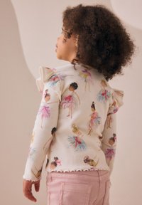 Langärmeliges geripptes Oberteil mit buntem Balletttänzer-Print, weißer Basis, gerüschten Schulterakzenten und gewelltem Saum; kombiniert mit rosa Hose.