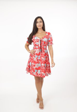 Vestito floreale rosso con maniche corte a sbuffo, scollo quadrato e dettaglio annodato sul davanti. Il tessuto presenta motivi floreali blu e bianchi.