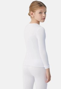 Top blanco de manga larga con escote redondeado y diseño ajustado. Material suave y elástico que resalta la silueta.