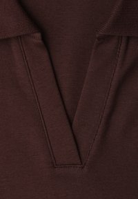 Close-up of a brown knitted fabric with a deep V-neck collar and visible stitching along the edges.