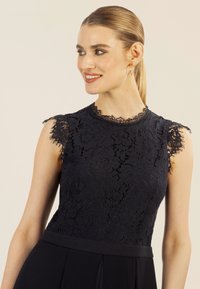 Vestido de encaje azul marino con un patrón floral, escote con formas onduladas y mangas cortas de encaje. La falda tiene un diseño suave y fluido.