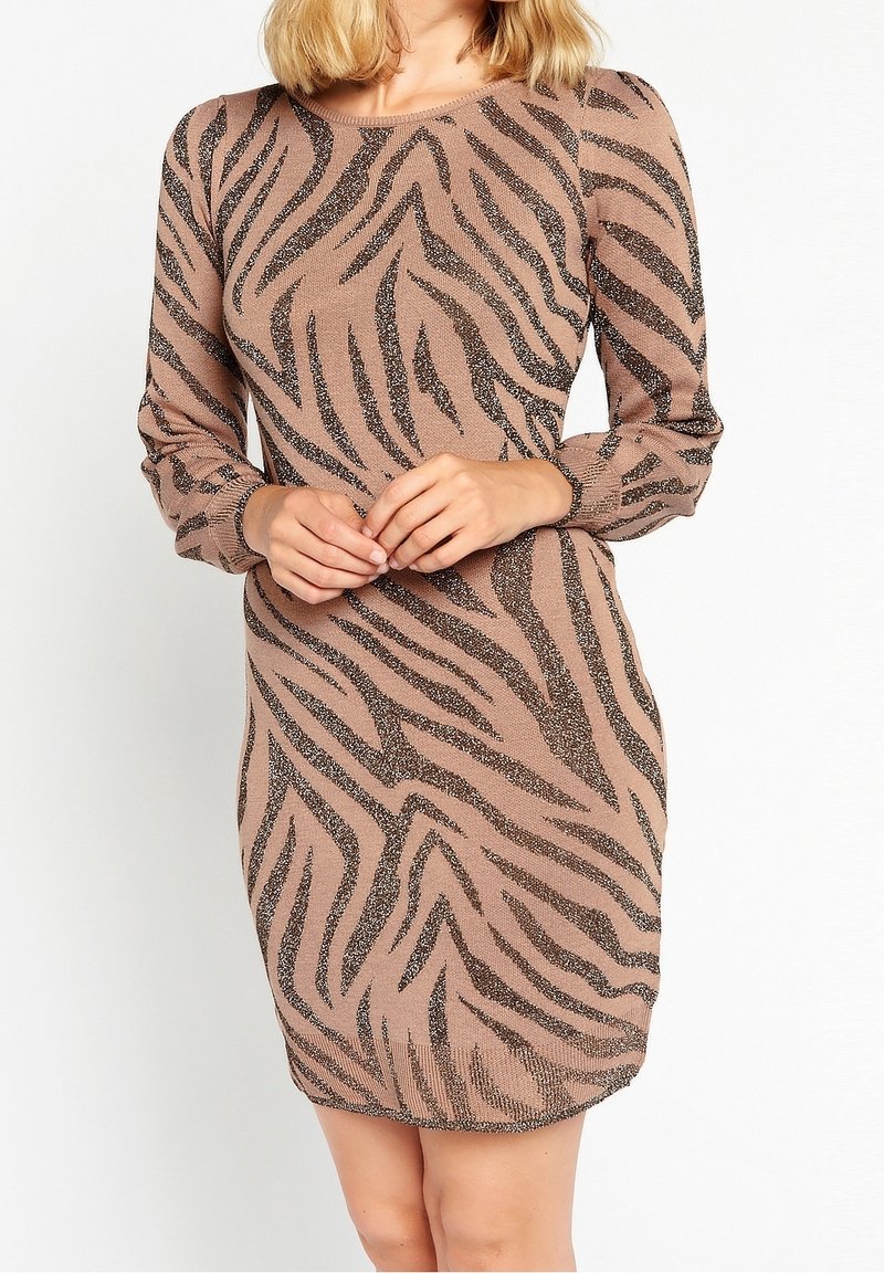 Abito in maglia beige con strisce zebra nere. Maniche lunghe, scollatura rotonda, forma aderente e texture scintillante per un tocco in più.