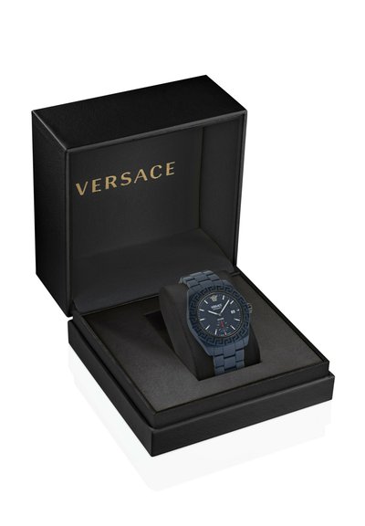 Fekete Versace karóra mintás kerettel és dátumkijelzővel, egy párnán bemutatva egy nyitott fekete dobozban, arany Versace logóval.