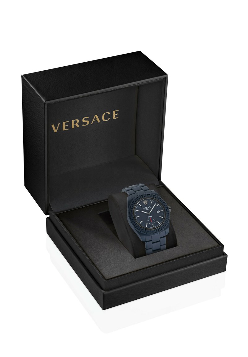 Zwarte Versace-horloge met een gemusterde bezel en datumaanduiding, gepresenteerd op een kussen in een open zwarte doos met het gouden Versace-logo.