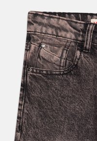 Jeans de mezclilla negros con un bolsillo frontal adornado con un embellecimiento en forma de corazón, textura desgastada y diseño clásico de cinco bolsillos.