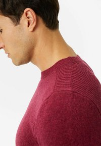 Burgunderfarbener Strickpullover mit einem strukturierten Muster im Schulterbereich, rundem Ausschnitt und glatter Oberfläche.