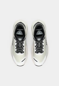 Ανοιχτό γκρι αθλητικά παπούτσια με μαύρες λεπτομέρειες, διχτυωτό άνω μέρος και λευκή καουτσούκ σόλα. Διαθέτει μαύρα κορδόνια και λογότυπο στην γλώσσα και στις πλευρές.