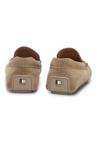 Brune mokkasiner i semsket skinn med rund tå, flate såler og en beige detalj på hælen som viser "BOSS"-logoen.