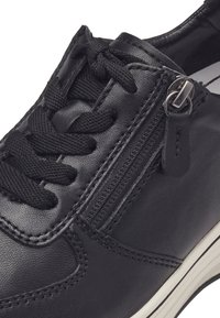 Czarne skórzane sneakersy z sznurowaniem, bocznym zamkiem błyskawicznym i białą gumową podeszwą. Posiadają teksturowaną powierzchnię i kontrastujące szwy.