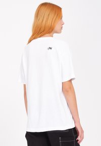 Witte katoenen t-shirt met een ronde hals, korte mouwen en een kleine grafiek van een mug op de bovenrug.