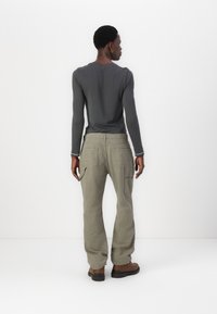 Μακριμάνικο γκρι π�ουκάμισο συνδυασμένο με ελαιώδεις cargo παντελόνες που διαθέτουν πολλές τσέπες, άνετη εφαρμογή και ίσια γραμμή. Χαλαρός, υφασμάτινος σχεδιασμός.